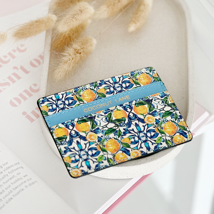 Yellow lemon print card holder on a white tray with dried grasses in the background.
