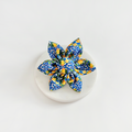 Yellow lemon-patterned fabric collar flower by Cocopup London on a round white surface with a plain white background.