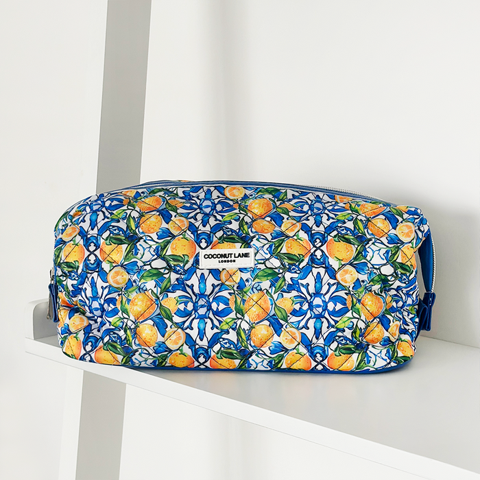 Expandable makeup bag with blue and orange Amalfi lemon print, displayed on a white shelf.
