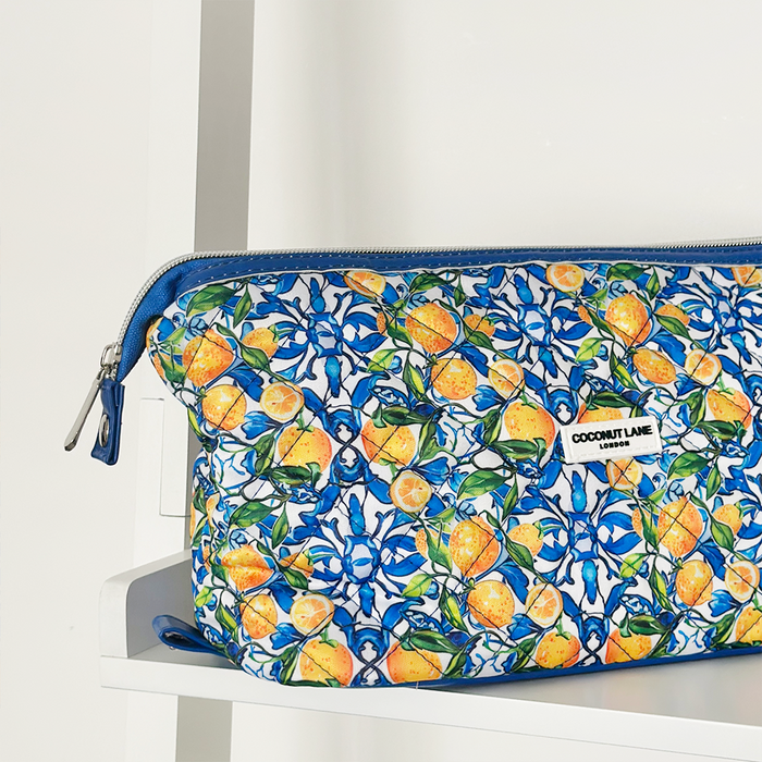 Yellow Amalfi Lemon expandable makeup bag with citrus pattern on a white shelf.