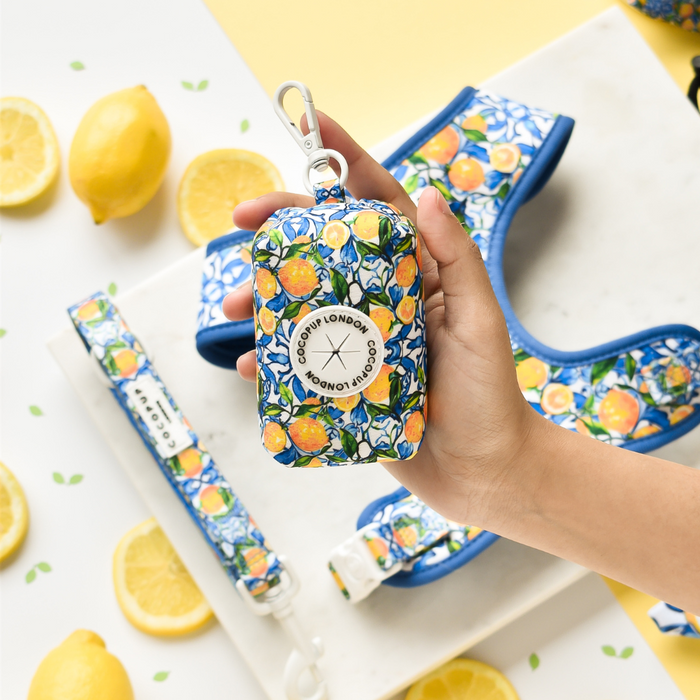 A hand holds a yellow Cocopup London poop bag holder with a lemon print.