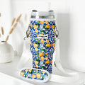 Yellow lemon-patterned tumbler carry case with white strap on a white shelf.