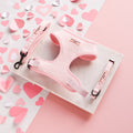 Baby pink heart-patterned harness, lead, and collar set on marble tile with scattered paper hearts.