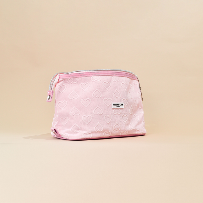 Light pink expandable makeup bag with heart pattern by Cocopup London on a beige background.