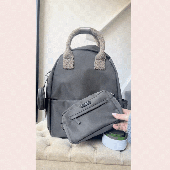 Mocha Cocopup London rucksack with fuzzy handles and matching pouch, held above a small white container.
