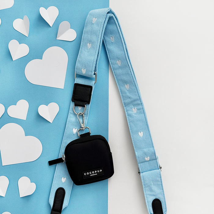 Blue cord bag strap with heart pattern and small black pouch, shown on a background with heart designs.