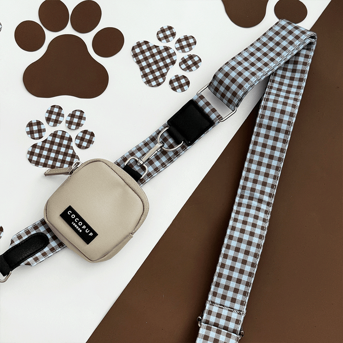 A brown and blue check print bag strap. with a beige treat pouch attached, for dog treats.