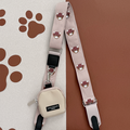 Beige Cocopup London crossbody bag with pink strap featuring Harold the Highland Cow and brown paw prints.