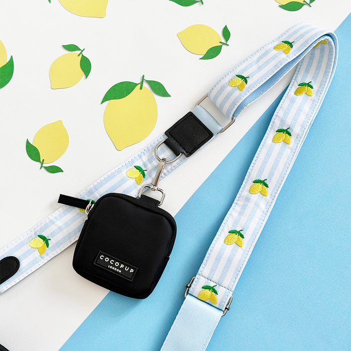 Lemon-print bag strap by Cocopup London on a small black dog bag, set against a matching lemon-patterned background.