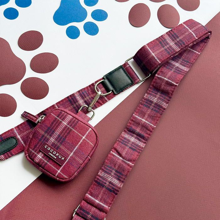 Maroon plaid crossbody dog walking bag with Mulberry Plaid Bag Strap, shown on a blue and brown paw print surface.