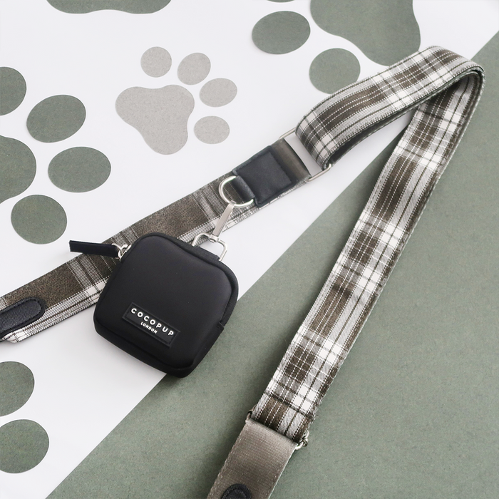 Plaid dog leash and black Cocopup London treat pouch with olive check strap on a paw print background.
