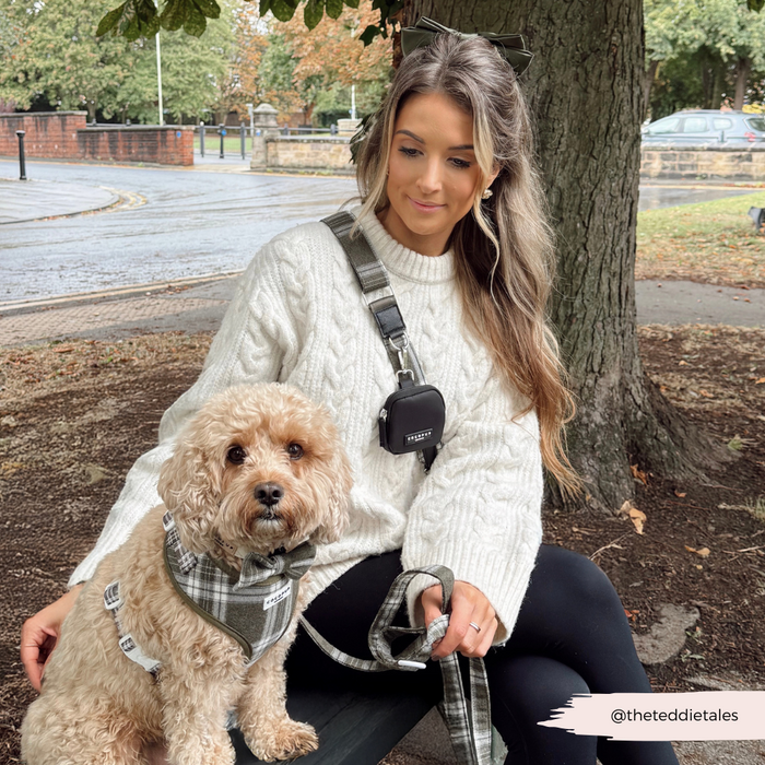 Woman in white sweater on bench with dog, Cocopup London Olive Check bag strap beside her.