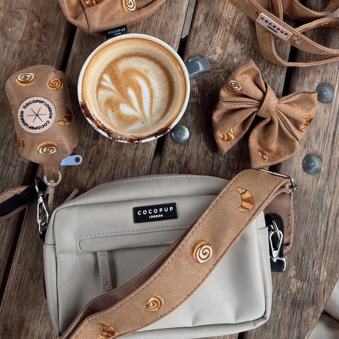 Cocopup Londons taupe bag strap with pastry pattern, next to coffee and matching taupe dog walking accessories.
