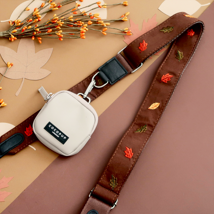 Beige pouch with Cocopup London label and leaf embroidery, attached to Pawtumn Leaves patterned bag strap.