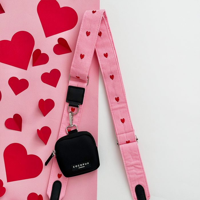 Pink heart-patterned cord bag strap by Cocopup London with small black dog walking bag and red paper hearts.