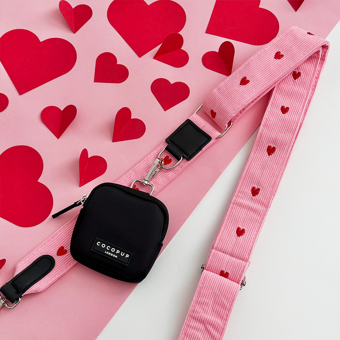 Small black Cocopup London bag with a pink cord strap featuring heart details.