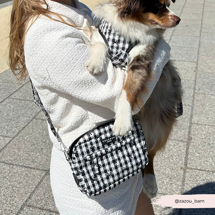 Woman in a white outfit with her dog, featuring Cocopup Londons Pup in Paris bag strap and a checkered accessory set.