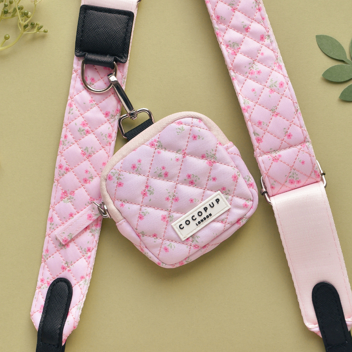 Quilted pink bag strap with ditsy floral pattern and matching pouch on a beige background.