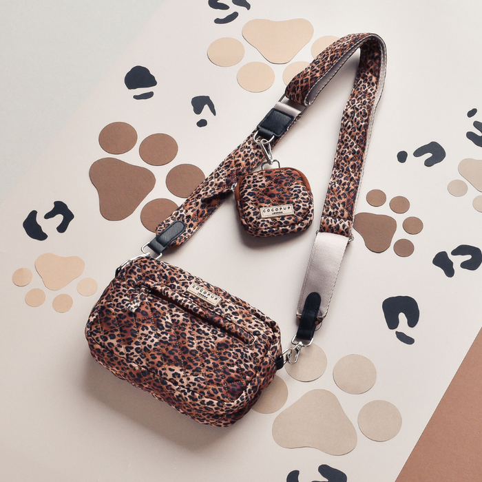 Quilted leopard print bag strap with matching leopard print bag and coin pouch on a paw print background.