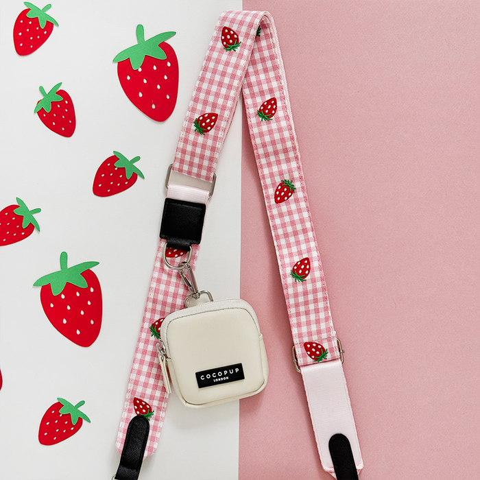 Strawberry-patterned Cocopup London bag strap with a small white pouch attached.