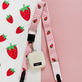 Strawberry-patterned Cocopup London bag strap with a small white pouch attached.