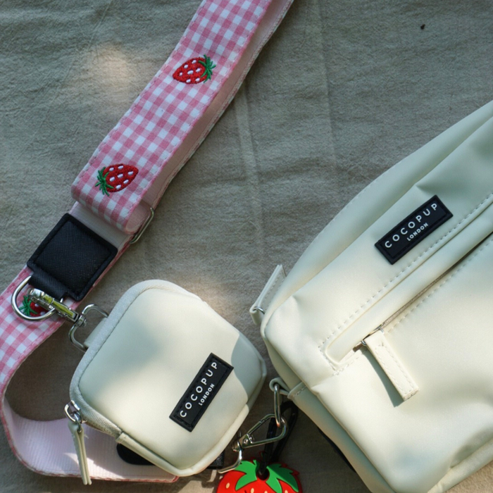 Cream-colored Cocopup London bag with a pink gingham Strawberry Picnic Pup strap.