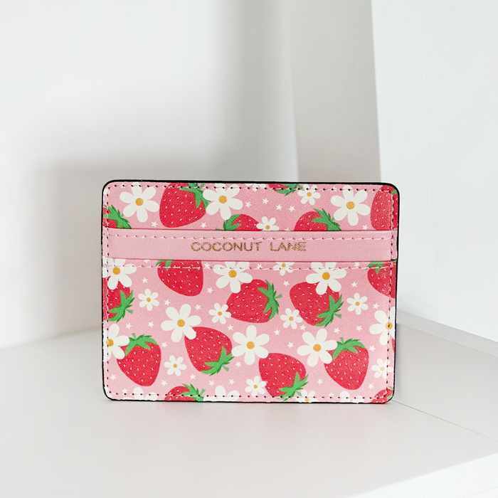 Pink Cocopup London card holder with strawberry and daisy prints on a white surface.