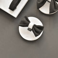 Black Cocopup London Aviator Bow Tie with a white center, displayed on marble against a gray background.