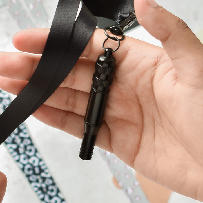 Cocopup London black training whistle with matching black lanyards held in a hand.