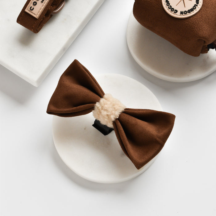 Brown Aviator bow tie and assorted dog accessories on marble, featuring warm tones and simple, stylish designs.
