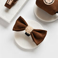 Brown Aviator bow tie and assorted dog accessories on marble, featuring warm tones and simple, stylish designs.