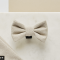 Brown tweed bow tie on light marble surface with a matching fabric swatch in the corner.