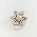 Brown tweed dog collar flower by Cocopup London displayed on a white round surface with white background.