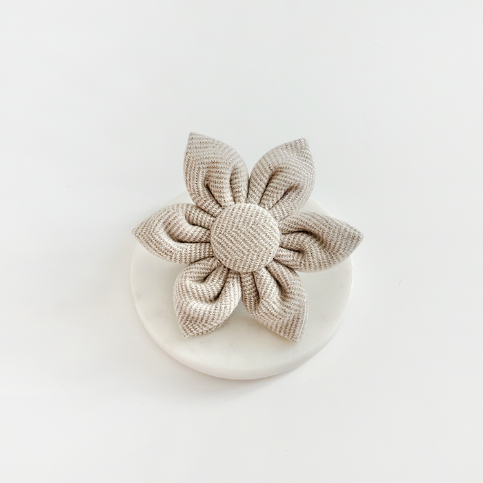 Brown tweed dog collar flower by Cocopup London displayed on a white round surface with white background.