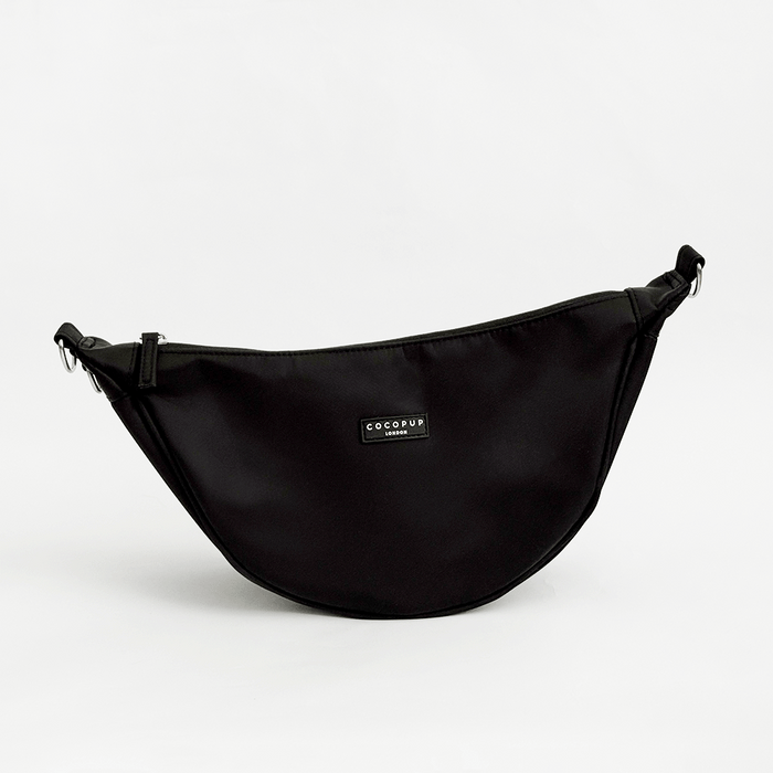 A plain black crescent shaped crossbody bag with silver metal hardware, set against a plain white background.