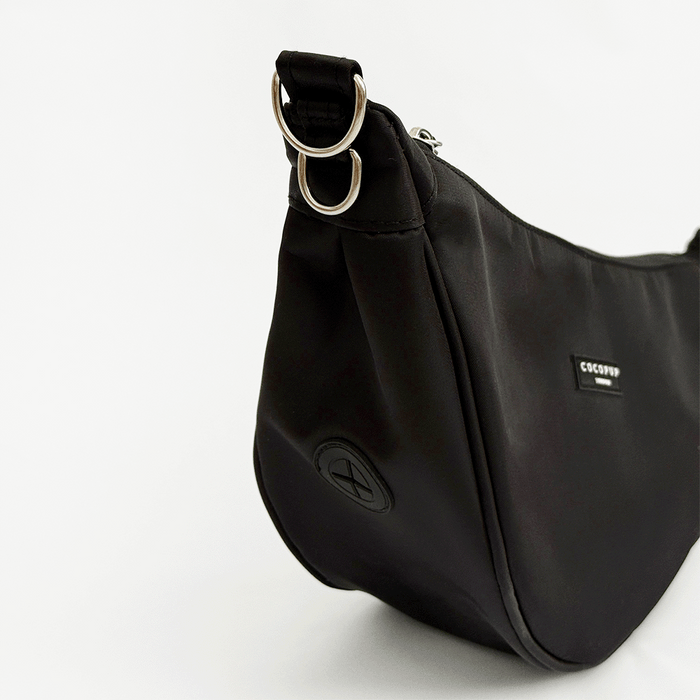 A plain black crescent shaped crossbody bag with silver metal hardware, set against a plain white background.