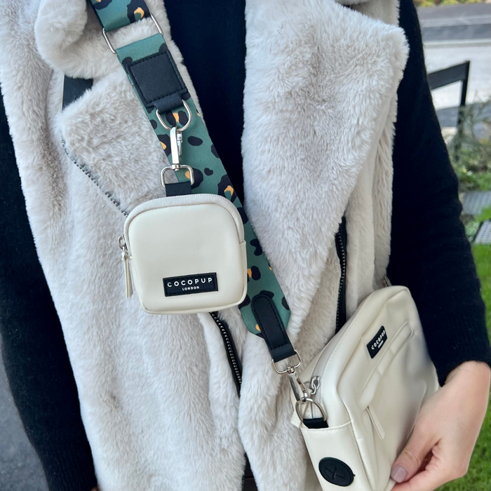 Person in a gray faux fur vest holds an Oyster White Cocopup London dog walking bag with attached treat pouch.