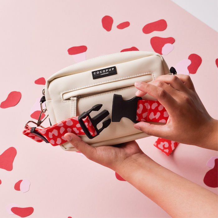 Red and pink leopard print bum bag attached to a cream dog walking bag against a pink background.