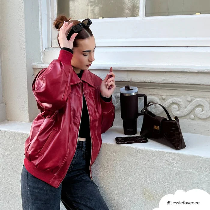Woman in a red leather jacket with jeans stands by a wall next to a burgundy Cocopup London tumbler.