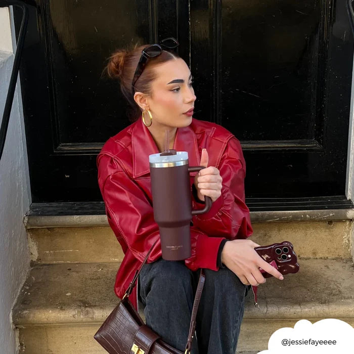 Woman in red jacket holding a burgundy Cocopup London stainless steel tumbler.
