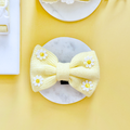 Yellow bow tie with white daisy pattern designed for dogs, from Cocopup London.