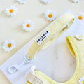 Yellow Cocopup London Buttercup Pup Lead with white daisy accents, displayed on marble next to a matching harness.
