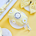 Pastel yellow Cocopup London poop bag holder with white daisy pattern and metal clasp.