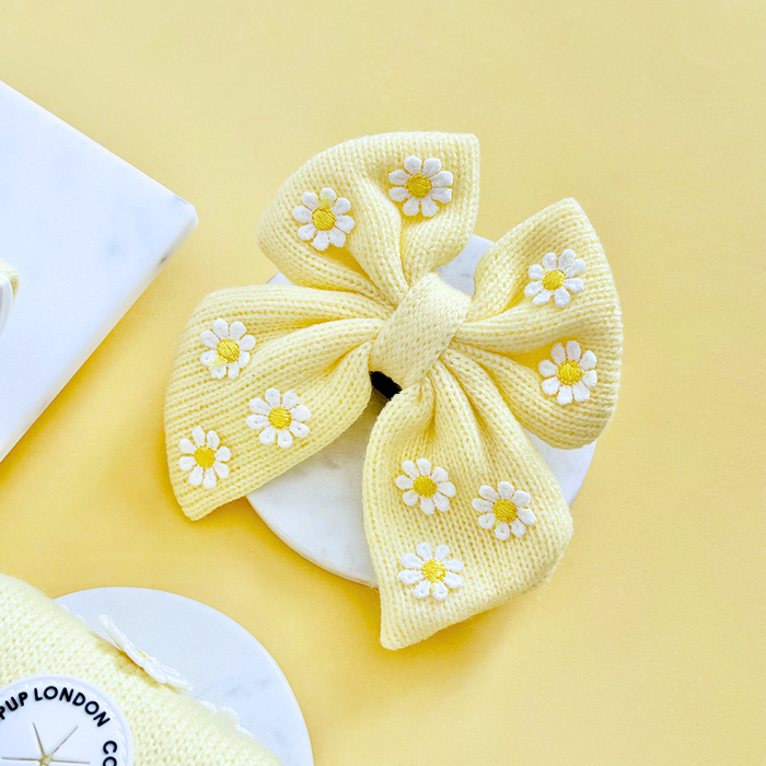Yellow daisy print sailor bow tie by Cocopup London, displayed on a white round surface with a yellow background.