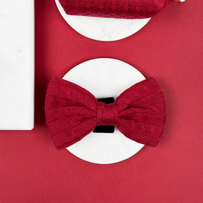 Mulled wine cable knit bow tie by Cocopup London displayed on a white circle with a red background.