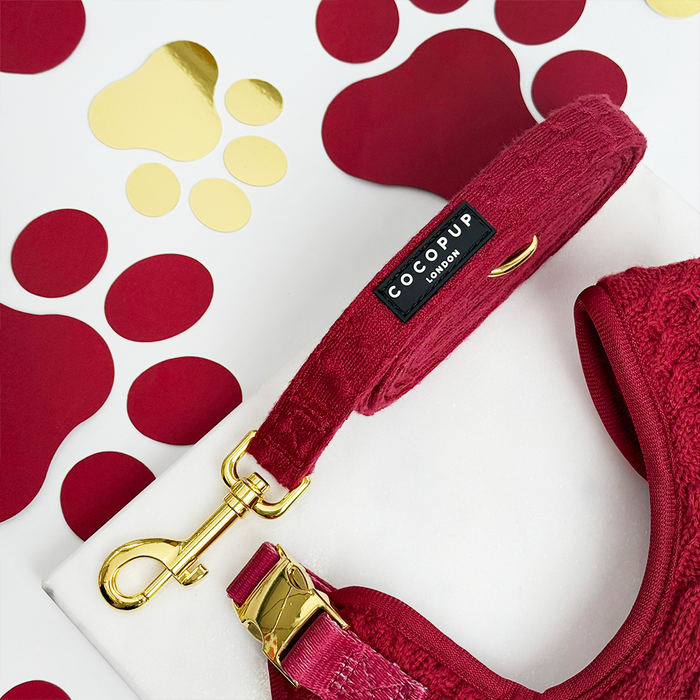 Mulled wine cable knit dog lead with gold hardware, displayed on a white surface with grey paw prints.