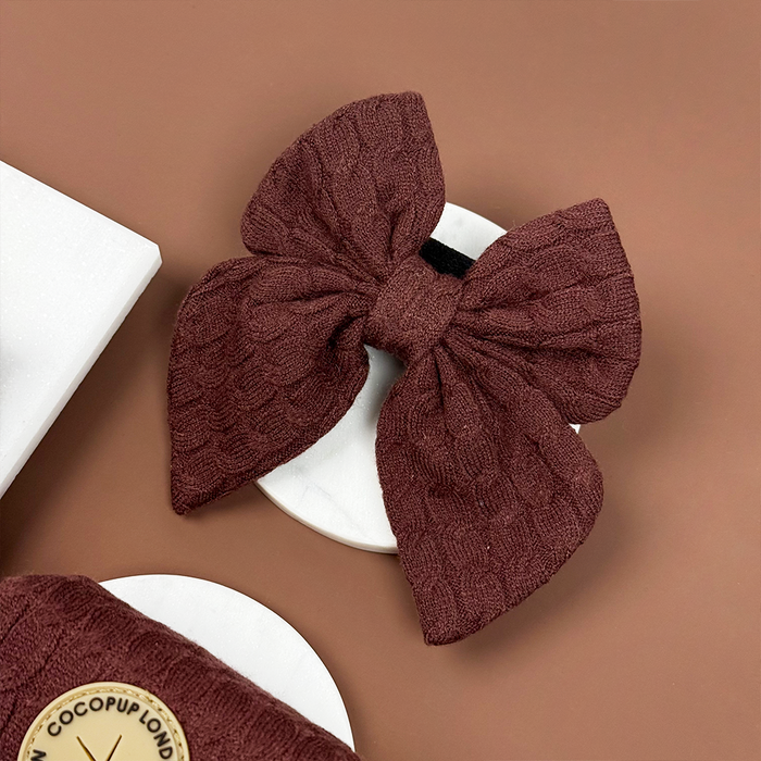 Brown cable knit sailor bow tie on a white coaster with a brown background.