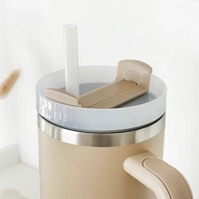 Caramel-colored stainless steel tumbler with handle, flip-top lid, and straw from Cocopup London.