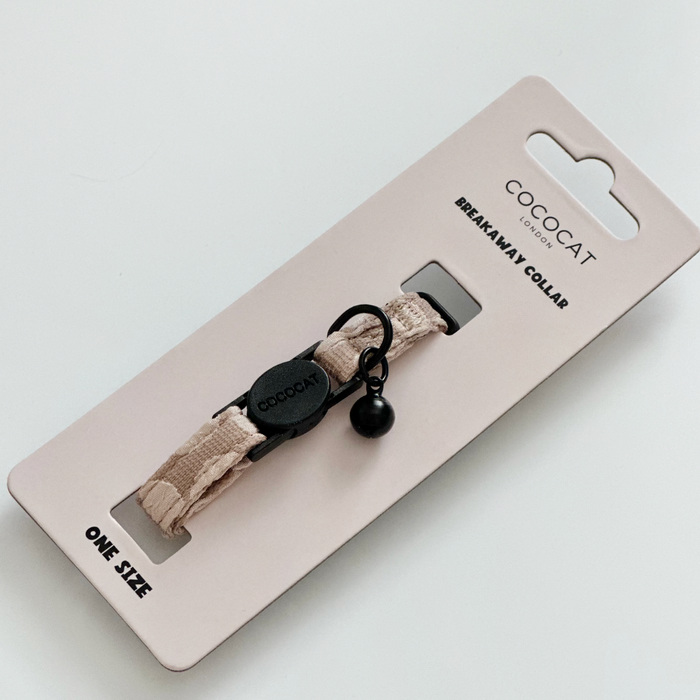 Mocha flower-patterned Cocopup London cat collar with breakaway buckle and bell, displayed on pink one-size packaging.