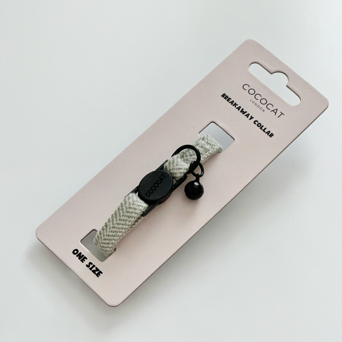 Sage tweed cat collar with herringbone pattern, breakaway buckle, and black bell on pink Cocopup London packaging.